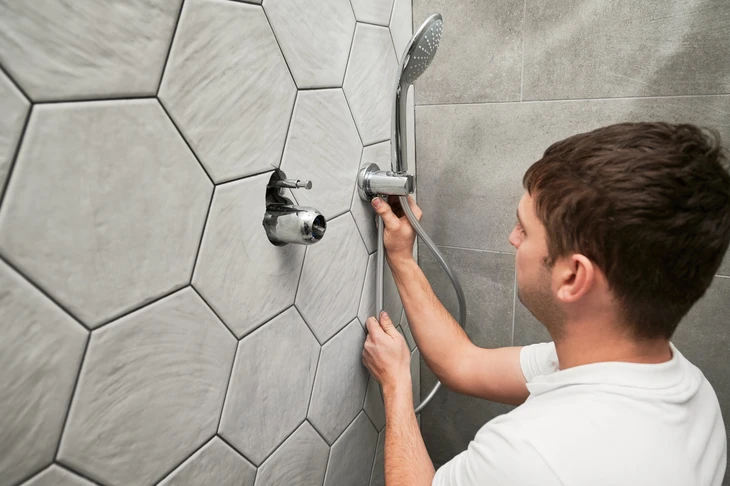 Un plombier installe un système de douche dans une salle de bain moderne
