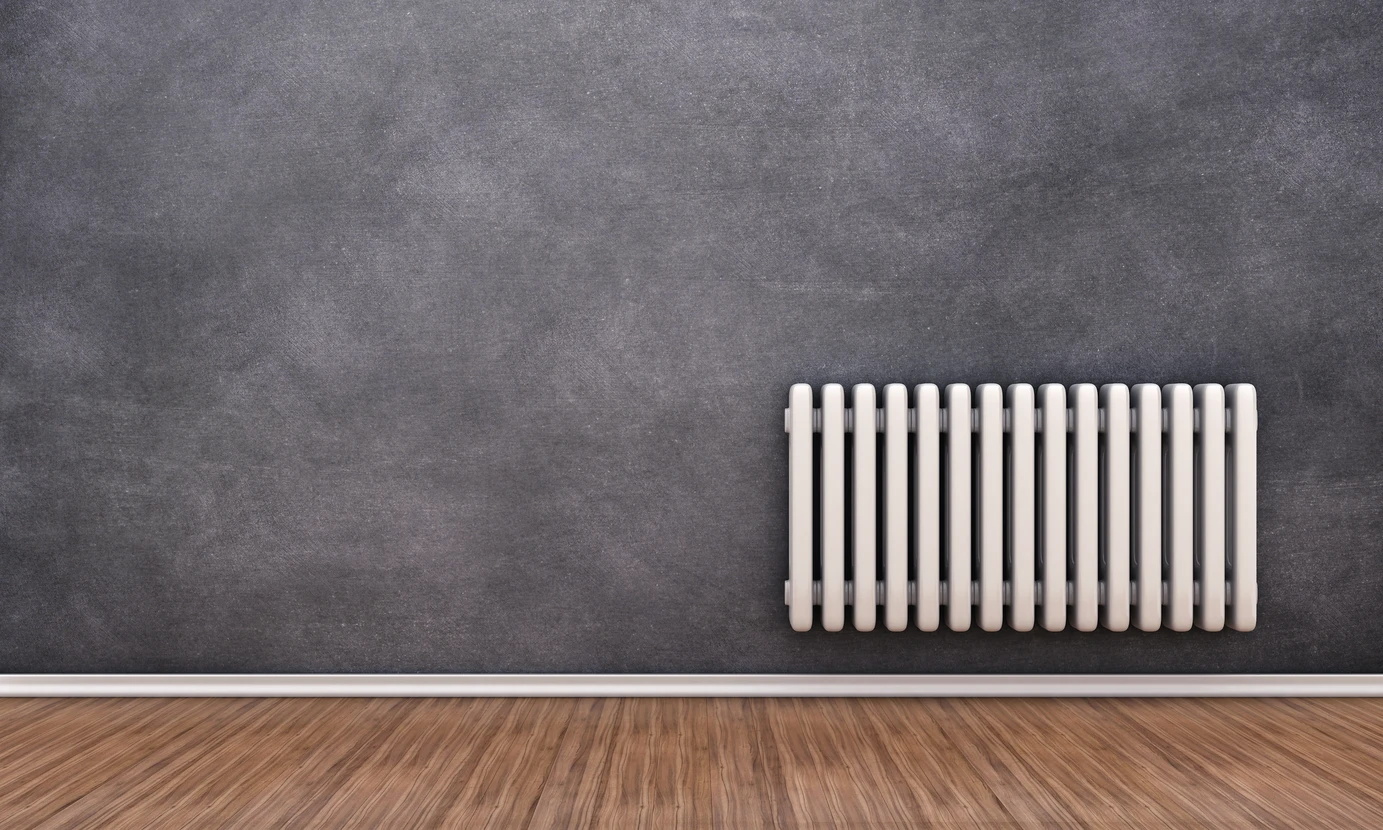 Intérieur résidentiel avec radiateur en fonte blanc classique fixé sur mur gris anthracite, parquet bois naturel au sol avec plinthe blanche