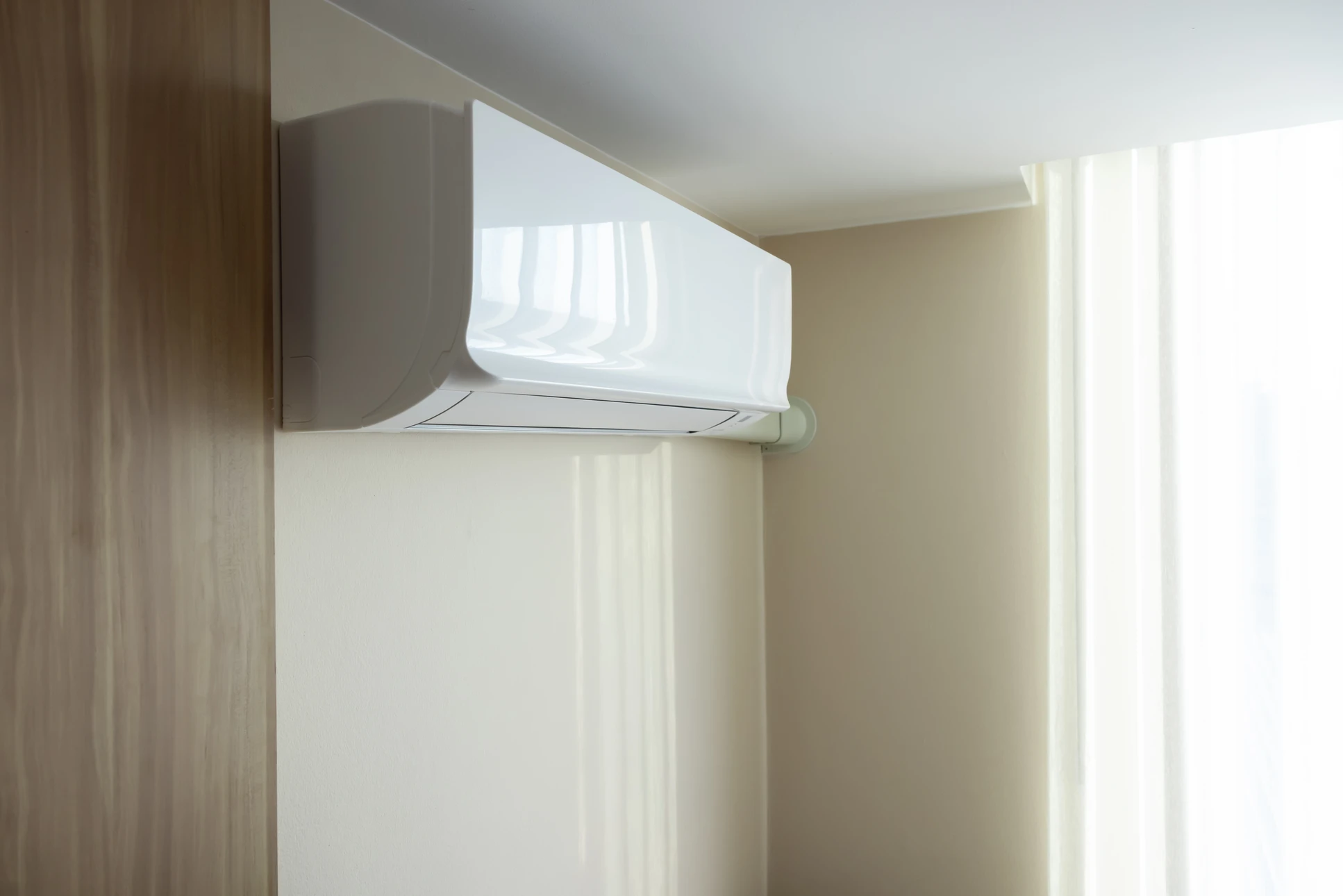 Fa&ccedil;ade ext&eacute;rieure en bois naturel d'une habitation avec climatiseur split mont&eacute; sur support m&eacute;tallique