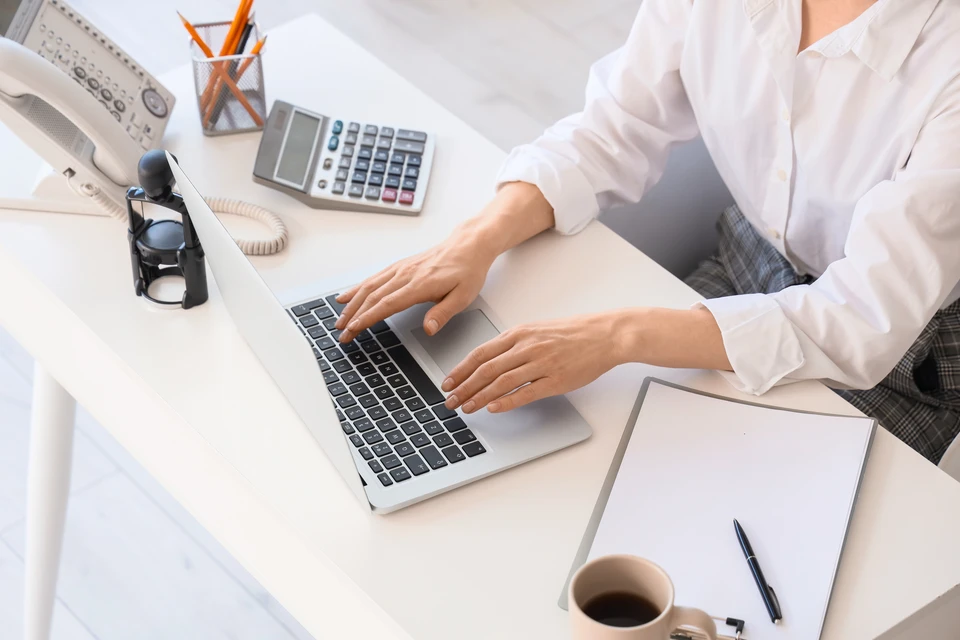 Photographie d'une personne assise &agrave; un bureau dans un environnement professionnel, accueillant un client ou occup&eacute;e &agrave; des t&acirc;ches administratives. L'arri&egrave;re-plan peut montrer un bureau organis&eacute; avec ordinateur et documents. L'image doit transmettre la disponibilit&eacute;, le professionnalisme et la confiance, refl&eacute;tant le r&ocirc;le de r&eacute;f&eacute;rent administratif et de coordination client.